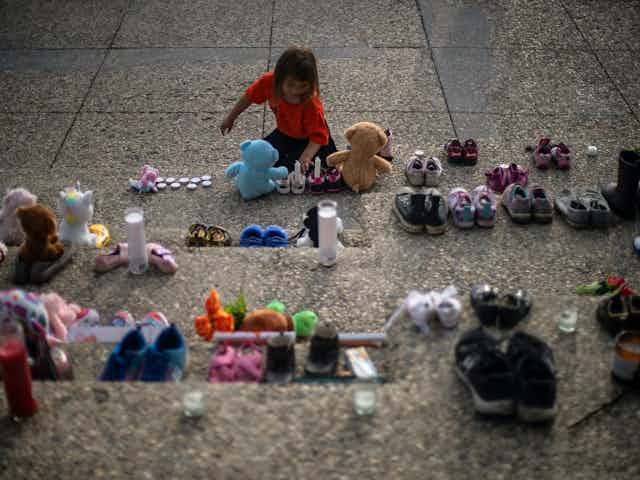 Shoes and toys line the steps of a building in Edmonton in honour of and mourning for the Indigenous children found in unmarked graves in Canada.