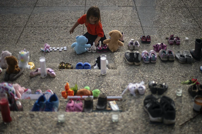 Shoes and toys line the steps of a building in Edmonton in honour of and mourning for the Indigenous children found in unmarked graves in Canada.