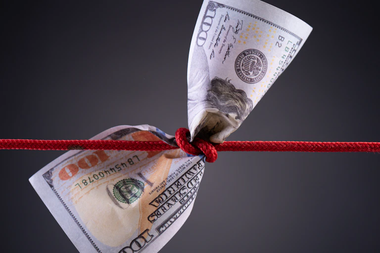 A $100 bill with a red cord tied around the middle.