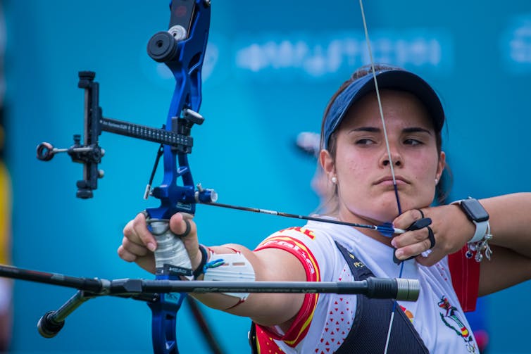 female archer pulls back the bowstring