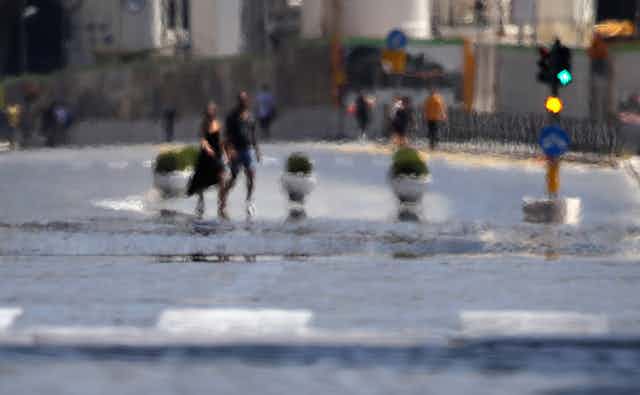 Heat comes off the pavement as people cross a street.