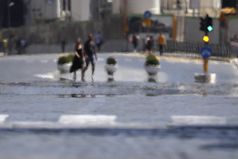 Heat comes off the pavement as people cross a street.