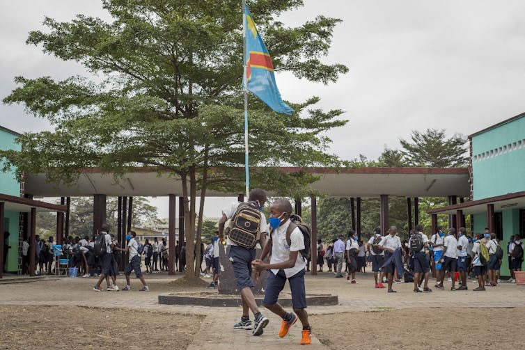 Des élèves masqués jouent dans une cour d’école à Kinshasa.