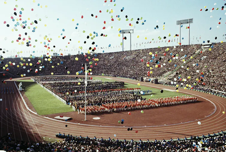 balloons fly over Olympians and spectators during the opening ceremony of the 1964 Summer Olympics at the National Stadium in Tokyo.