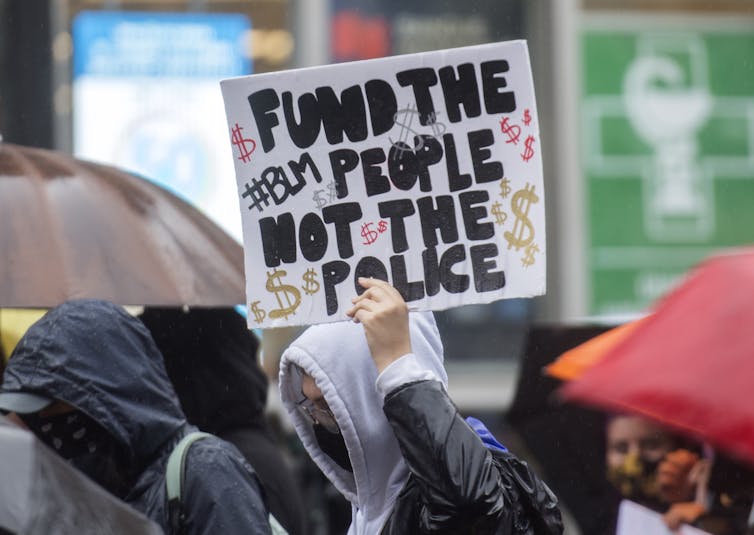 Un cartel en una manifestación dice: 'Financia a la gente, no a la policía / BLM'