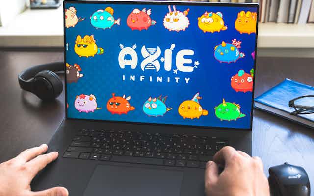 A laptop showing Axie Infinity with someone's hands on the keyboard