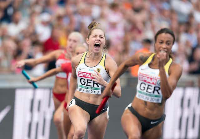 Two female runners compete in a relay track and field race