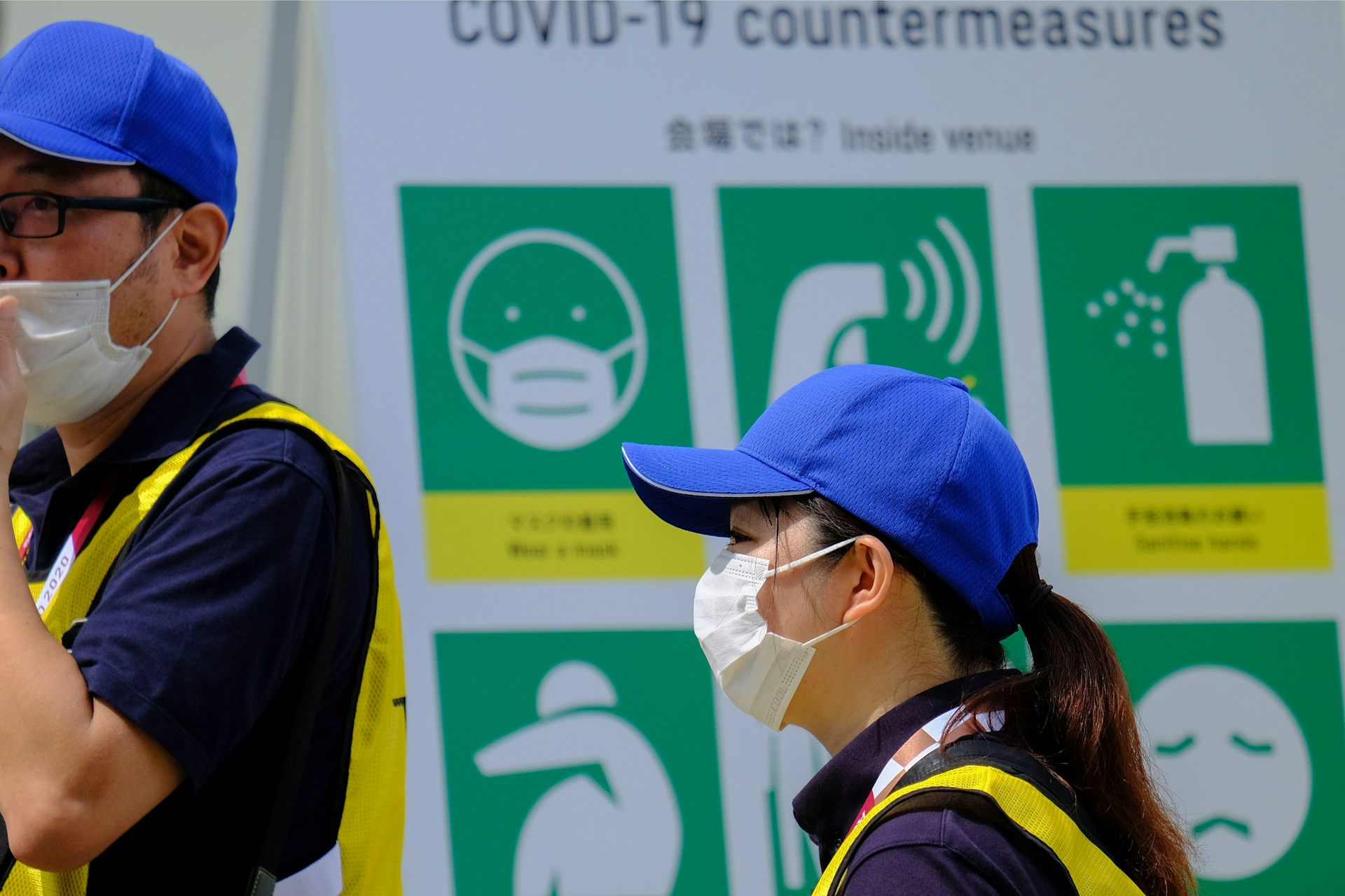 Volunteers in masks attend to an Olympic site in Tokyo