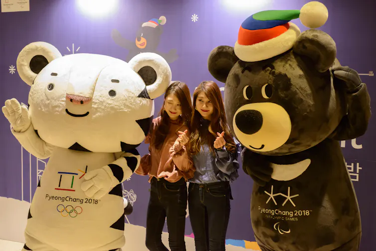 Fans pose with a tiger and bear sports mascot.