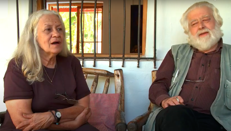 a man and a woman, grey-haired and animated as they talk.