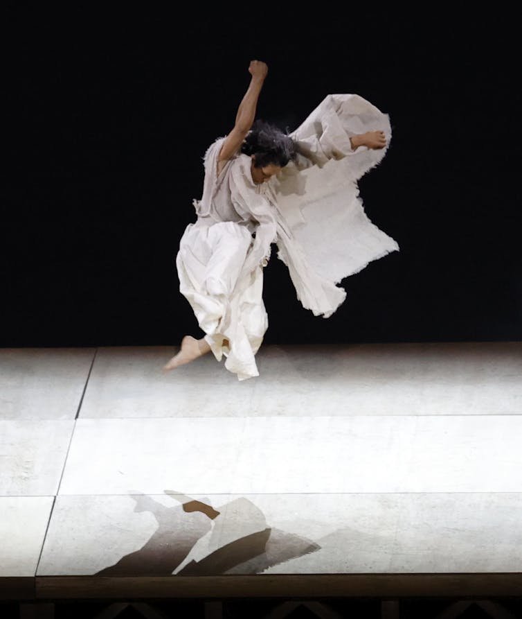 A man in white, mid leap.