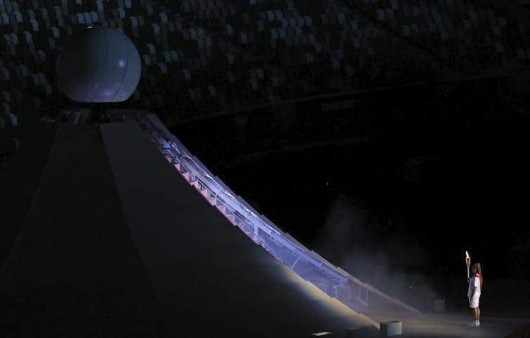 Naomi Osaka looks up at the Olympic flame.