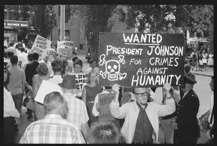 Sign reads 'wanted: President Johnson for crimes against humanity'