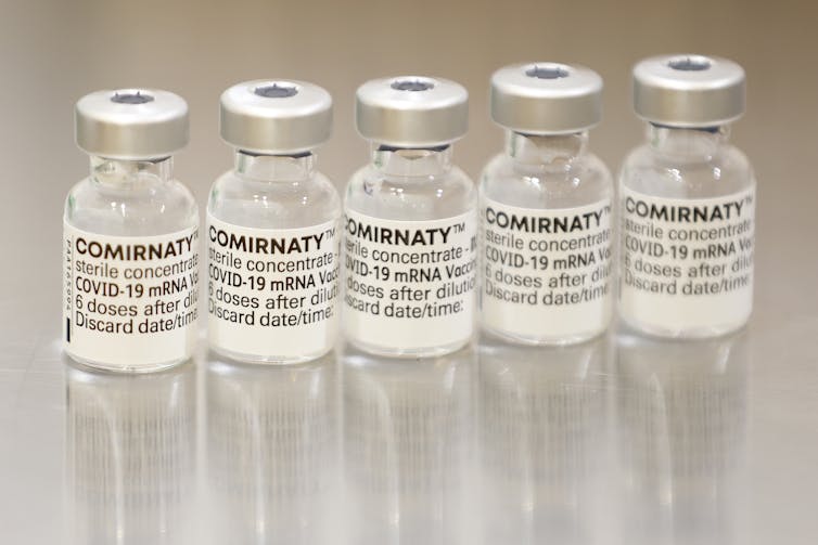 Five vials of the Pfizer vaccine lined up in a row.