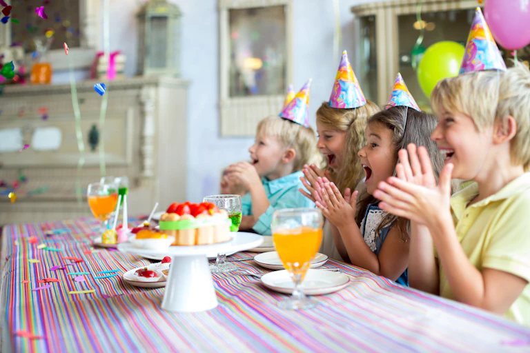 Excited children at a child's birthday party clap.