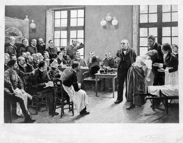 Une gravure d’un homme tenant une femme qui s’est évanouie alors qu’il s’adresse à une salle pleine d’étudiants masculins