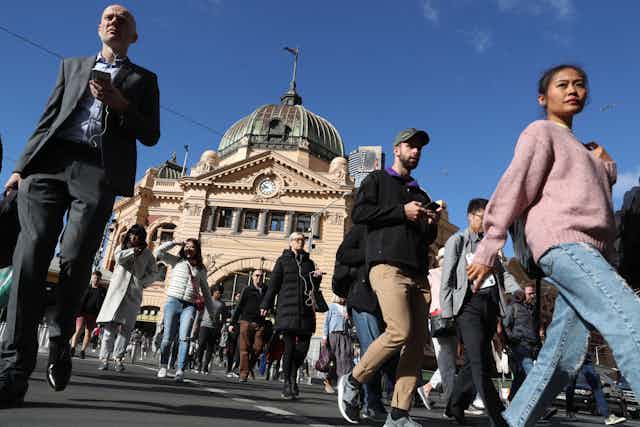 Pedestrians cross the road outside Flinders St Station in Melbourne. 