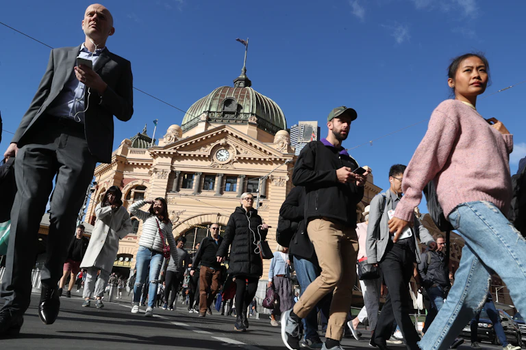 Pedestrians cross the road outside Flinders St Station in Melbourne.