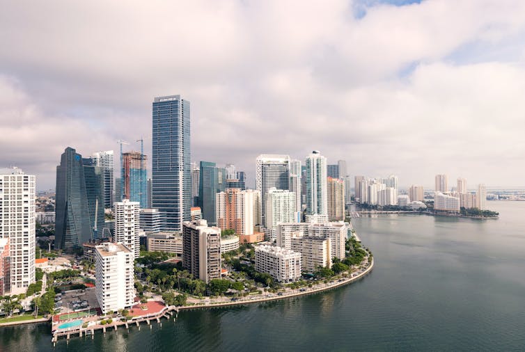 An aerial view of downtown Miami showing waterfront walking paths, parks and pools