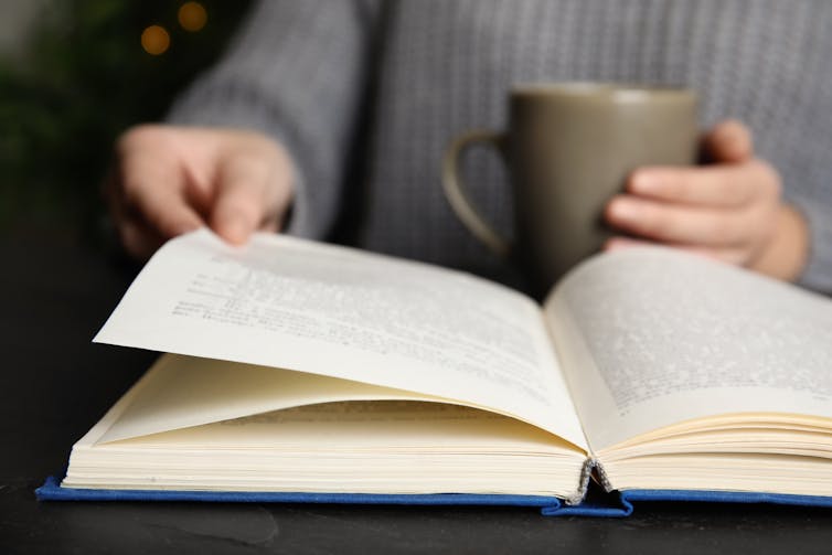 Person reading book with a cup of tea.