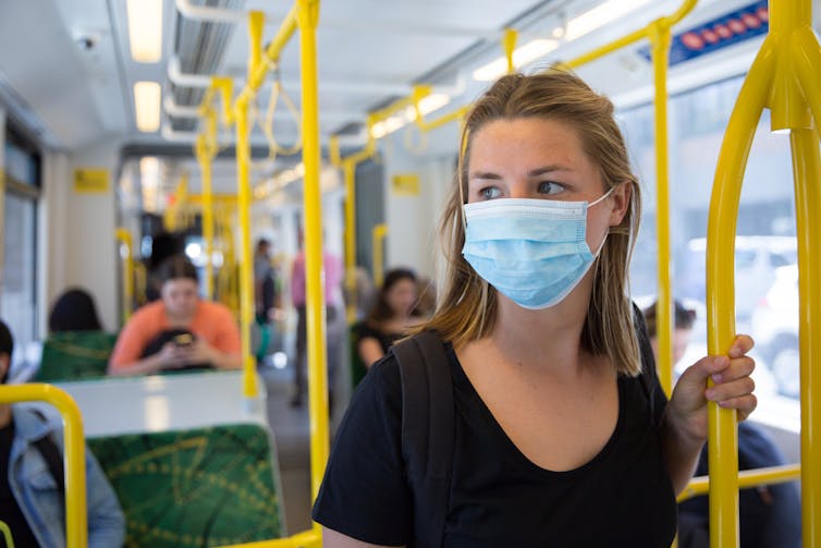 A woman wearing a face mask on a bus