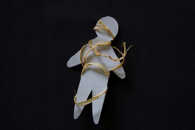 Cut-out paper shape of child bound in string