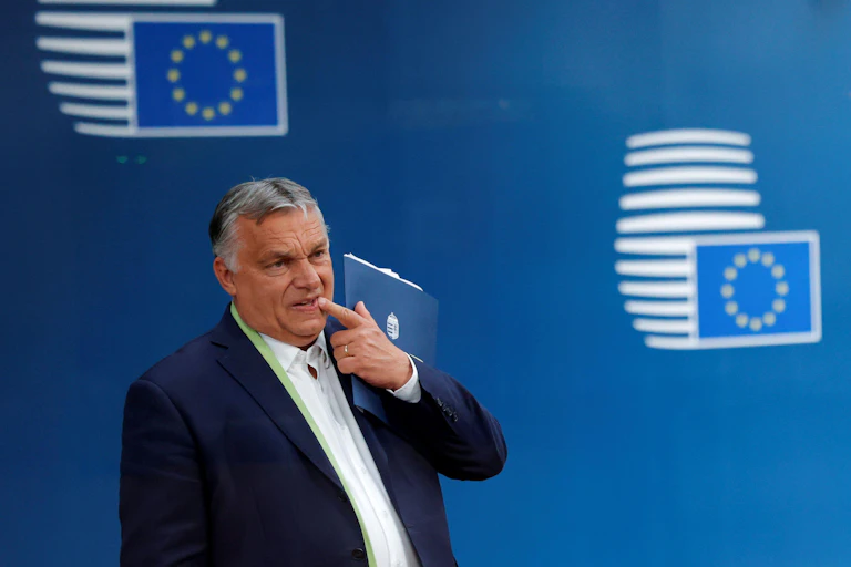 Viktor Orban standing in front of a backdrop printed with EU flags