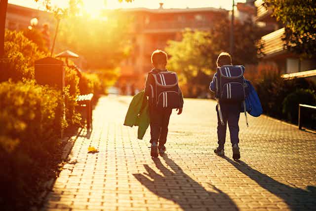 Two little boys wearing backpacks walk together
