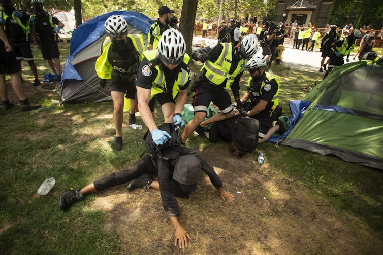 Police arrest people in a homeless encampment