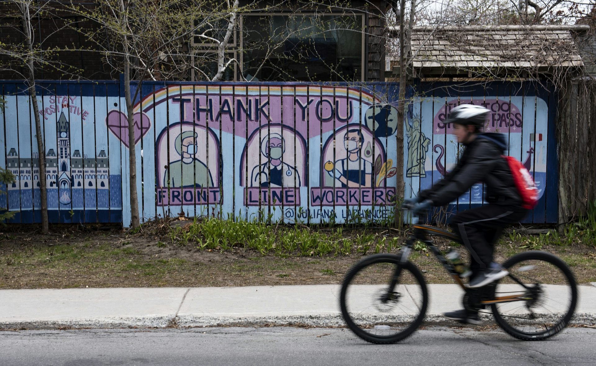 A cyclist passes a mural thanking front-line workers for their efforts during the COVID-19 pandemic