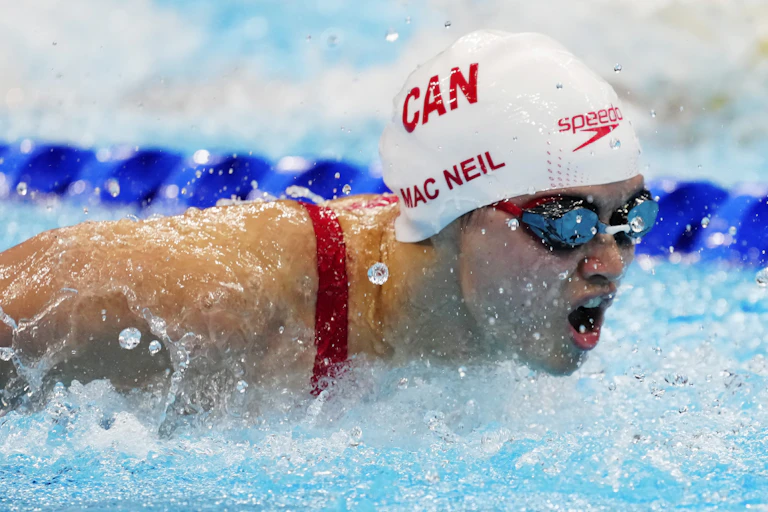 Margaret Mac Neil is shown with her mouth open as she completes a butterfly stroke.