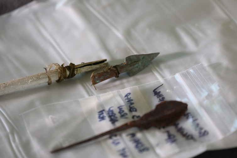 two metal arrowheads, one lashed with sinew to a wooden shaft