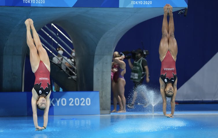 Two divers are about to enter the water simultaneously.
