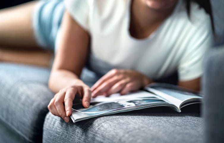 Girl lying on the couch reading magazine