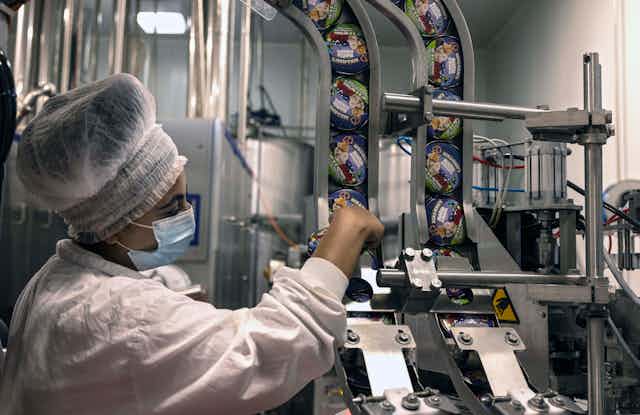 A woman operates a machine loaded with Ben & Jerry's ice creams