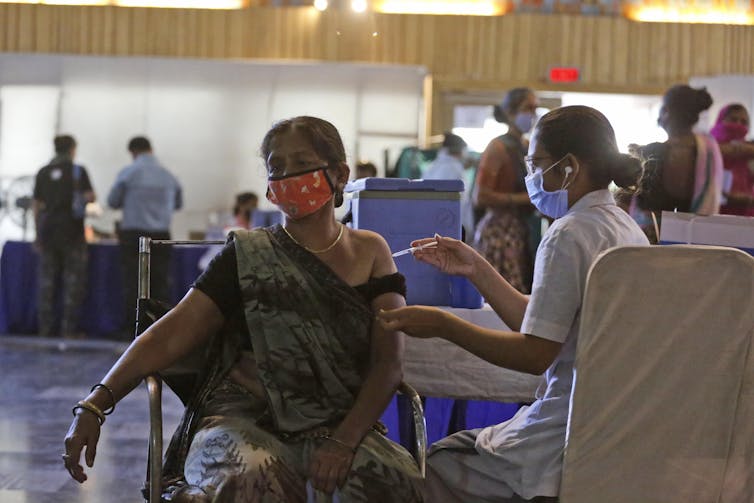 Indian woman in sari receiving a vaccine.