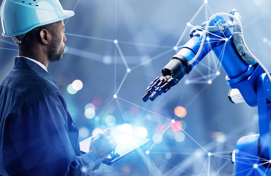 Operative in a hard hat inspecting a robotic arm