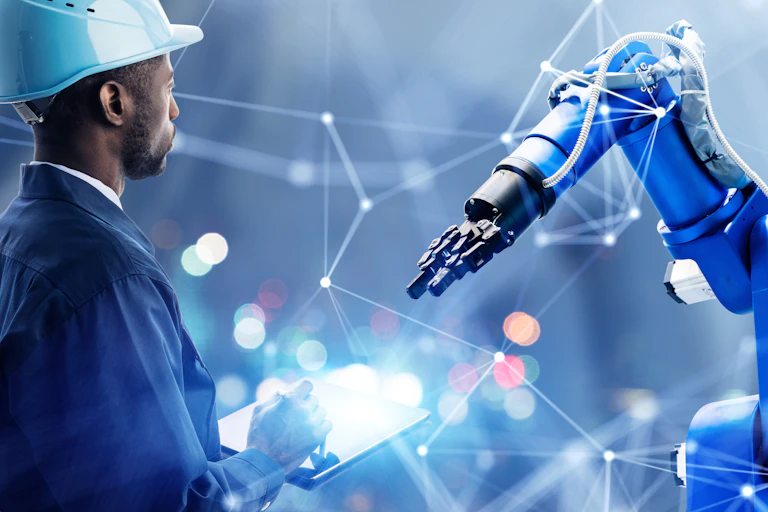 Operative in a hard hat inspecting a robotic arm