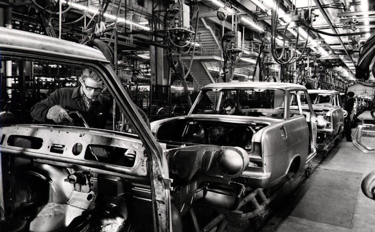 Man working on car assembly plant in 20th century