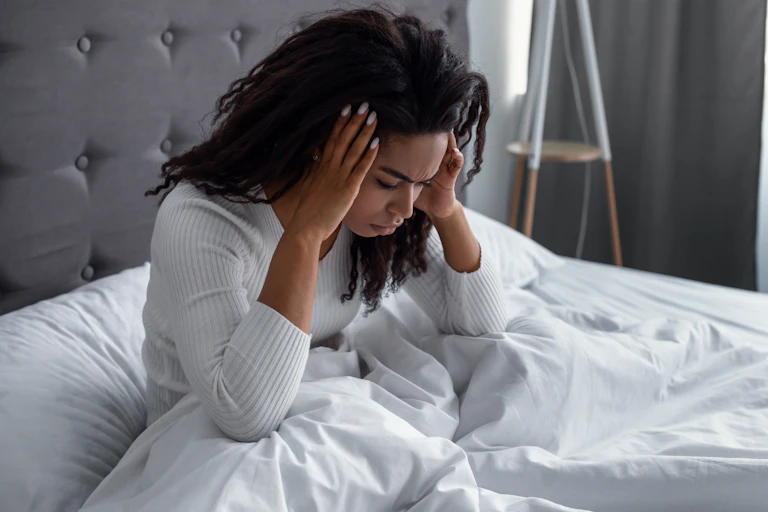 A woman in bed holding her head