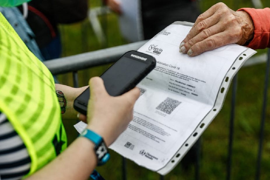 A person hands over a print-out of their health pass to an official. 