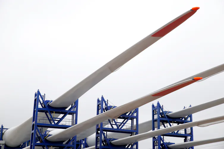 Three wind turbine blades arranged on scaffolding.