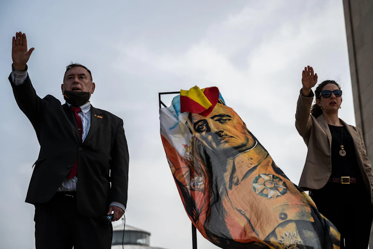 A man and a woman give the fascist salute next to a flag with the image of Spanish dictator Francisco Franco, March 2021.