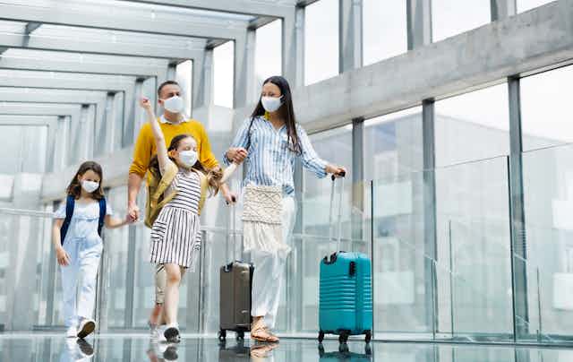 Family of four walk through the airport with masks on