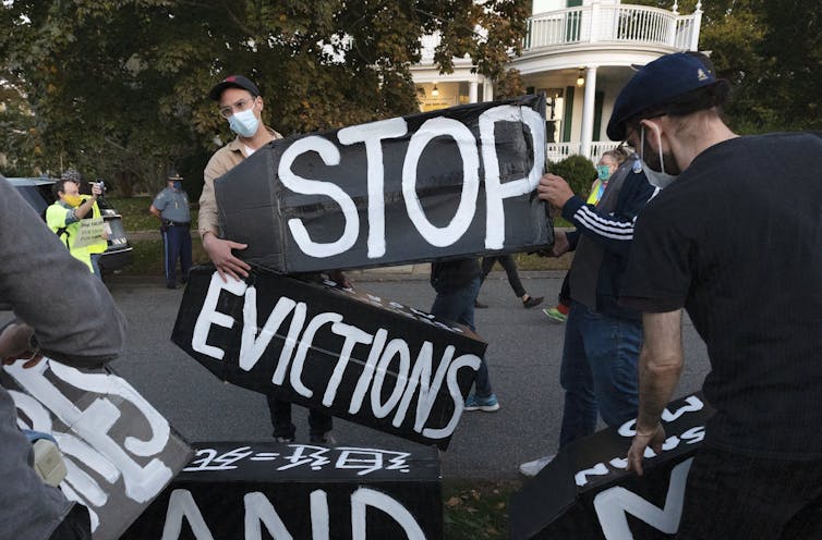 Protesters with large signs displaying the words Stop Evictions