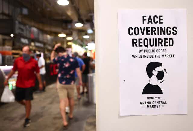 a sign requiring face coverings in a busy indoor market