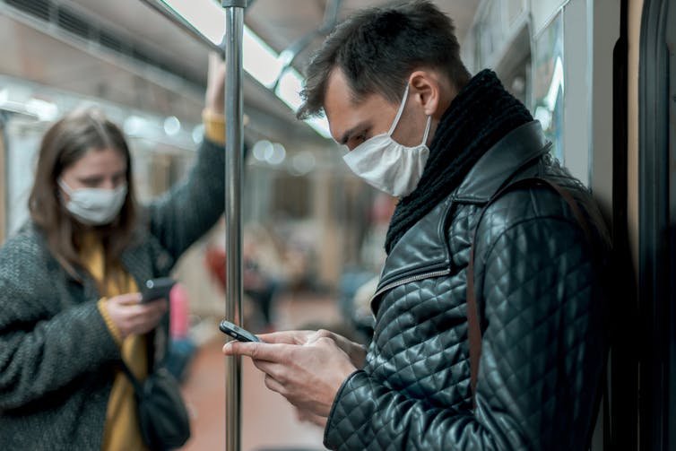 Young man on a train looks at his phone.