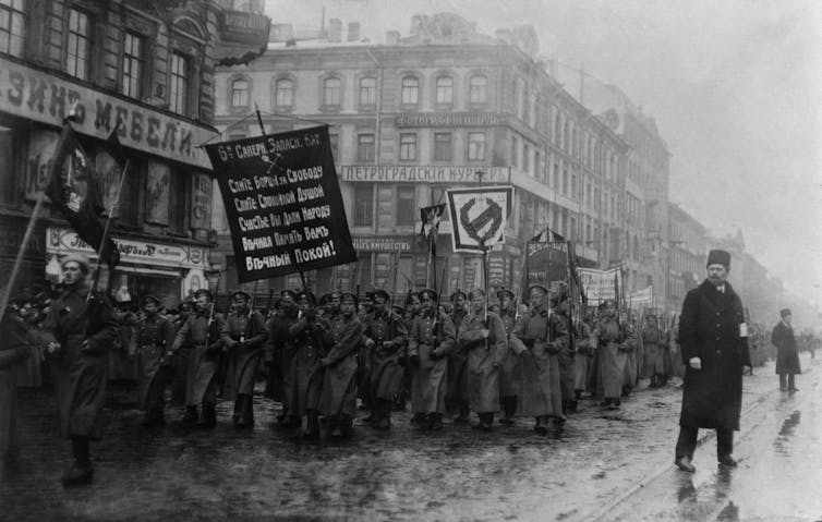 Russian men marching in the street with banners.