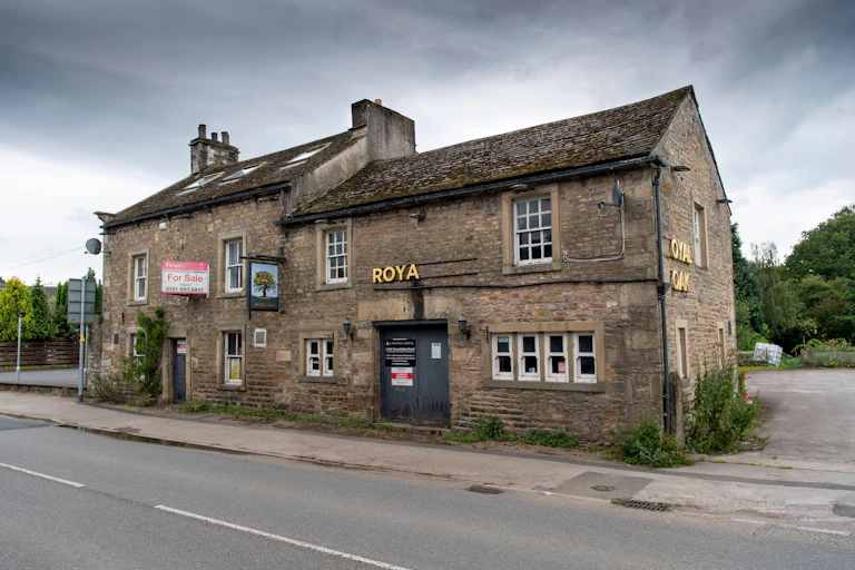 A boarded up pub with half its sign missing.