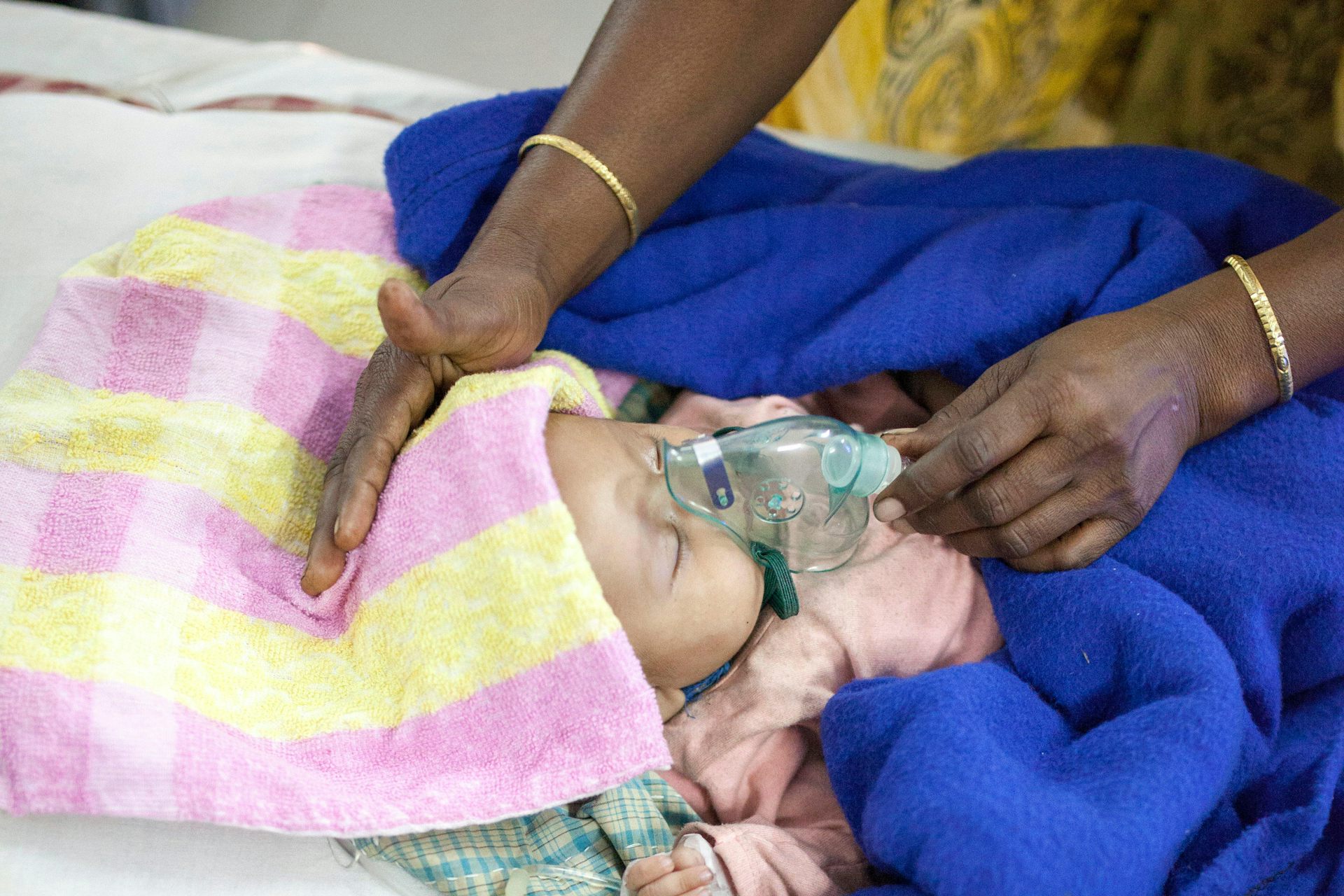 A mother nebulises a child with severe respiratory illness